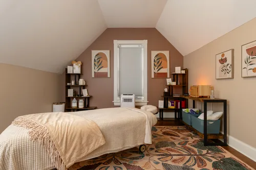 Treatment room in soft neutrals with botanical prints and open shelving
