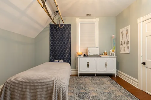 Treatment room in sage green with anatomy reference and hot towel cabinet