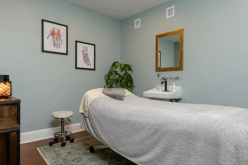 Treatment room with reflexology charts, a plant, and an in-room sink