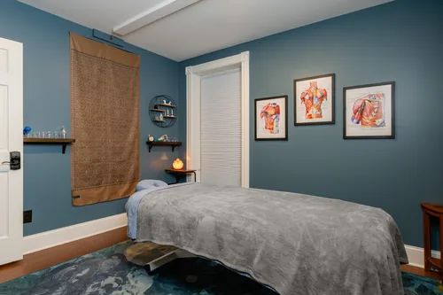 Treatment room with deep blue walls and anatomical wall art